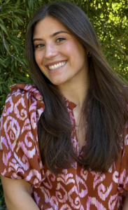 A headshot of Madeleine Morris with greenery behind her.