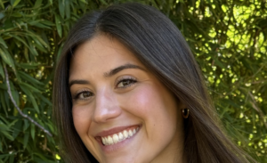 A headshot of Madeleine Morris with greenery behind her.